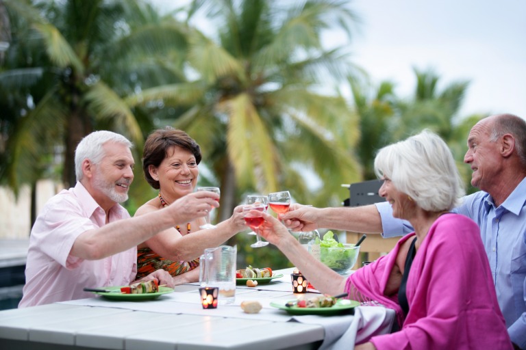 senior_group_enjoying_vacation_bbq_cheers_cocktails_mature_couples